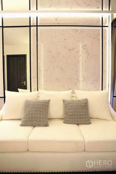 Condominium for rent in Watthana, Bangkok - White three-seat sofa with grey cushions against marble-style accent wall.