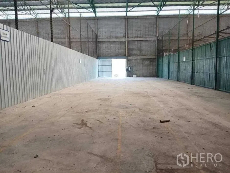 Warehouse for rent in Prawet, Bangkok - Wide clear-span warehouse bay facing a large sliding loading door and masonry back wall.