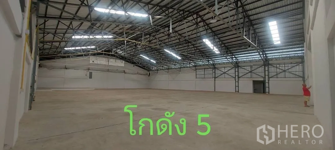 仓库 for rent in Bueng Kum, Bangkok - 仓库内部，钢桁架屋顶与采光板，混凝土地面。