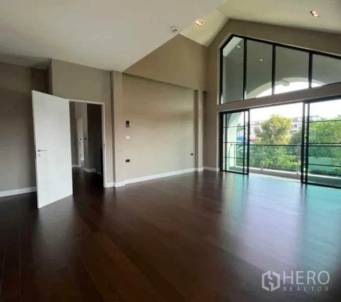 Detached House for sale in Mueang Nonthaburi, Nonthaburi - Spacious upper room with timber floors and large windows opening to a balcony.