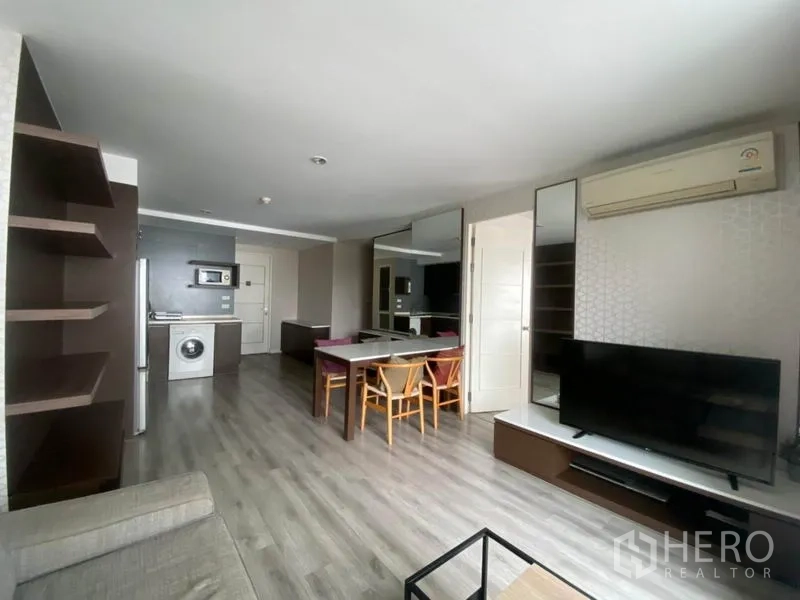 Condominium for rent in Watthana, Bangkok - Spacious open-plan living area with TV console, shelving, and a dining set.