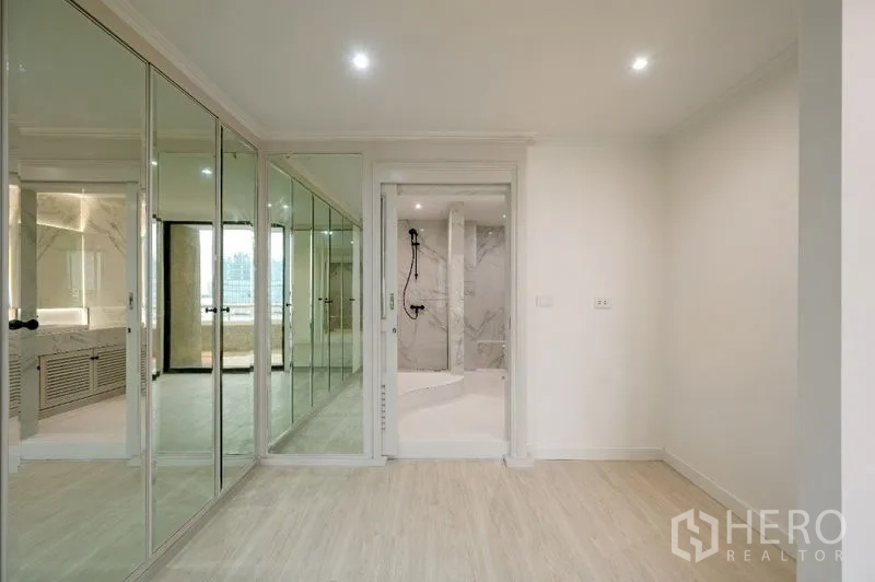 Condominium for sale - Bedroom corner with mirrored wardrobes and doorway to a marble shower.