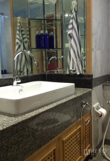 Condominium for rent in Pathum Wan, Bangkok - Modern bathroom vanity with granite countertop, square basin, mirrored cabinet, and chrome faucet.