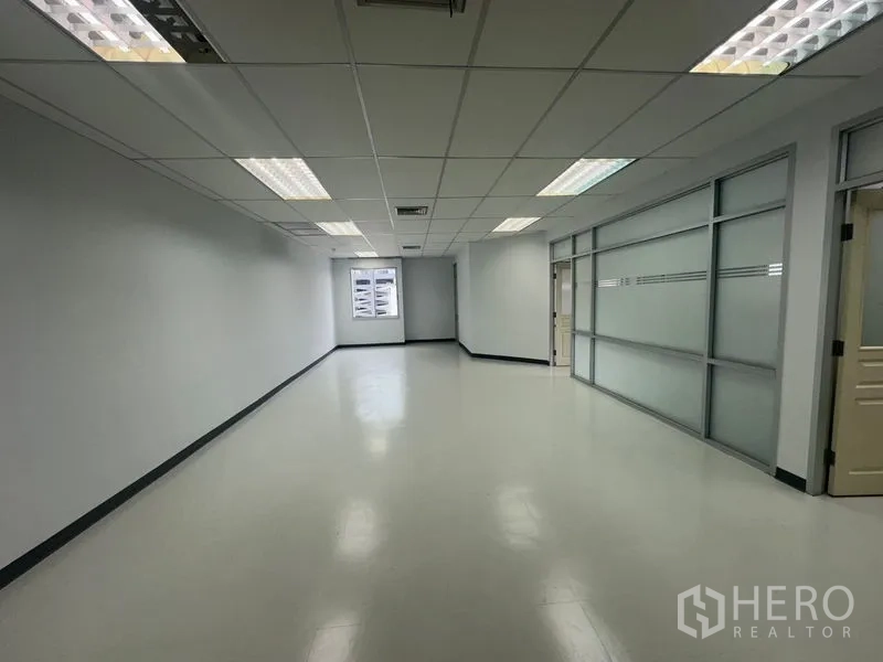 办公空间 出租在Bang Rak, Bangkok - 狭长工作区，尽头有窗，右侧为磨砂玻璃墙。