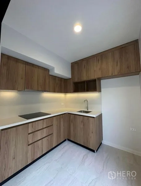 联排别墅 出租在Yan Nawa, Bangkok - L形厨房，木纹橱柜、电磁炉与橱柜下照明