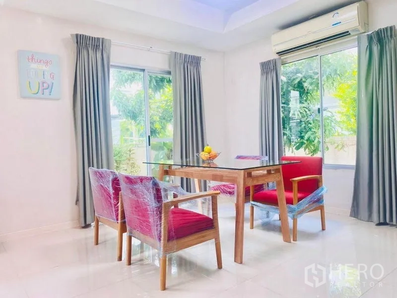 Detached House for rent - Dining area with glass table, red armchairs and corner windows overlooking the garden.
