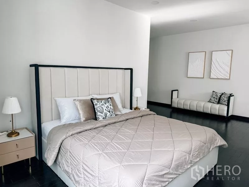 Detached House for rent or sale in Bang Phli, Samut Prakan - Guest bedroom with upholstered headboard bed, long bench and neutral decor.