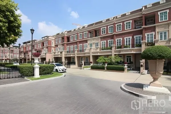 Townhouse for sale in Watthana, Bangkok - Facade view of European-style red-brick townhouse row with landscaped drive.