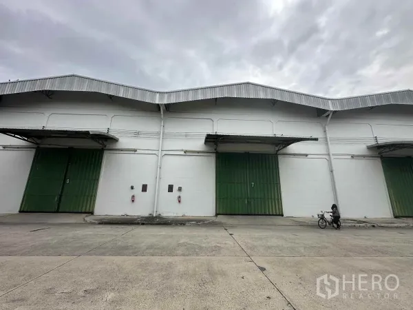 货栈 出租在Bang Pa-in, Phra Nakhon Si Ayutthaya - 仓库立面，两扇大型绿色卷帘门与带雨棚的装卸月台。