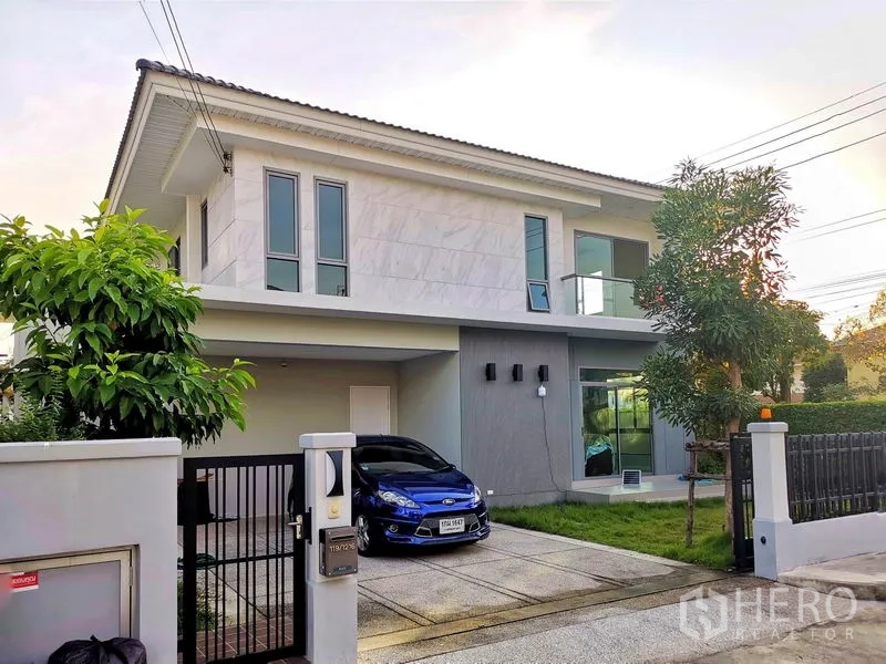 Detached House for sale in Nonthaburi - Angled exterior view showing driveway gate, covered parking and a glass balcony.