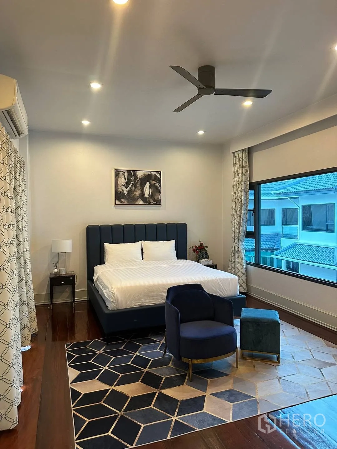 บ้านเดี่ยว for rent in Watthana, Bangkok - ห้องนอนเตียงหัวเตียงสีน้ำเงิน เก้าอี้อาร์มแชร์ และพรมลายเรขาคณิต