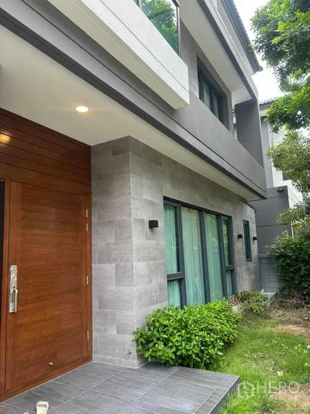 บ้าน ให้เช่าในMueang Nonthaburi, Nonthaburi - ทางเข้าหน้าบ้าน ประตูไม้สัก ผนังหินสีเทา และพุ่มไม้สวนหน้าบ้าน