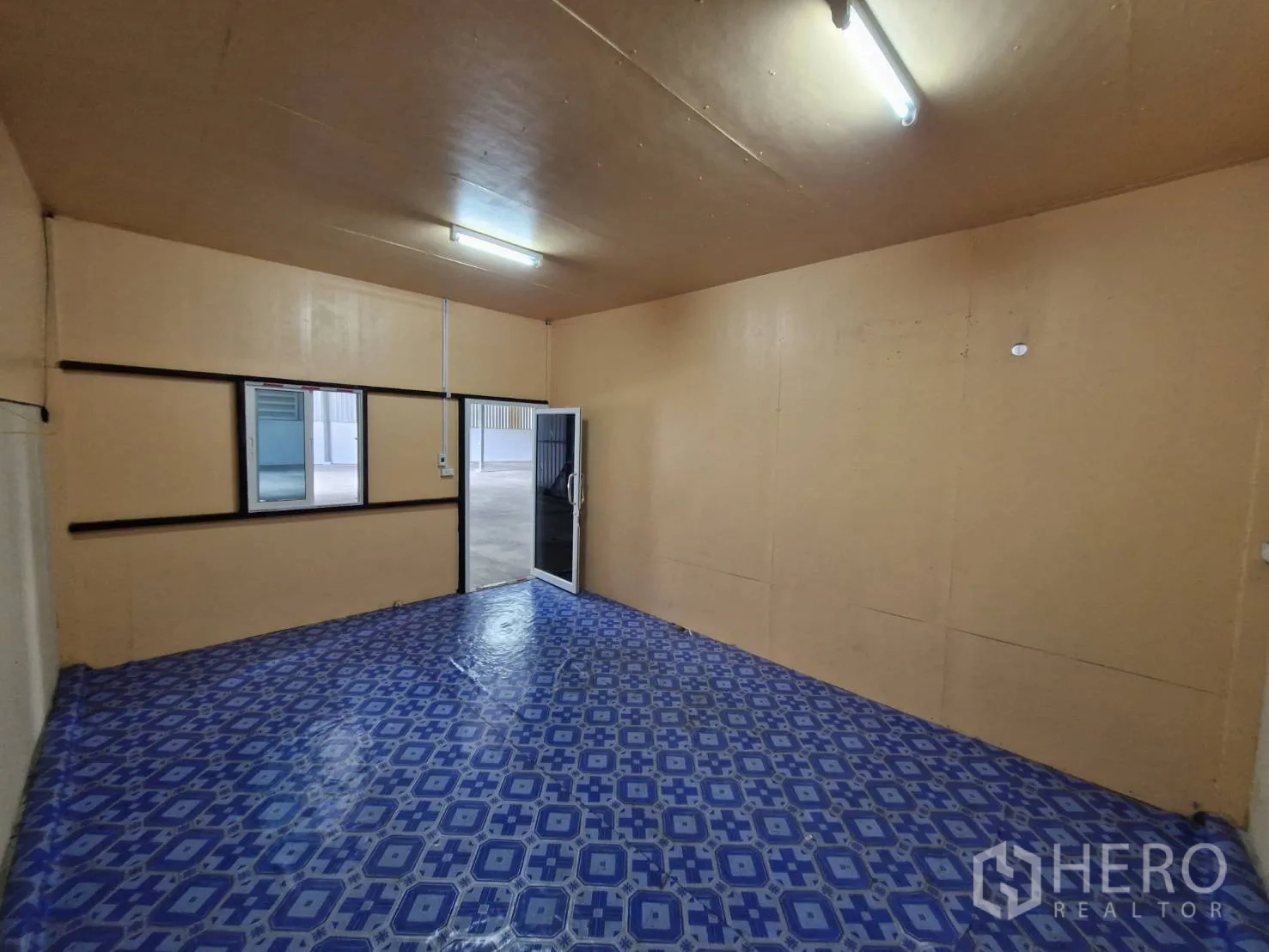 Warehouse for rent in Nakhon Pathom - Office interior facing the warehouse, blue tiled floor and sliding glass door.