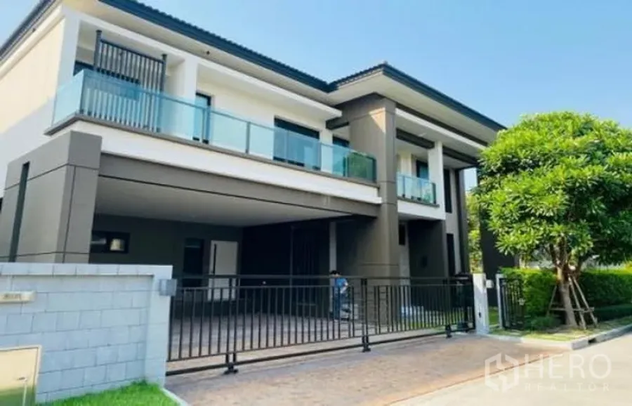 Detached House for sale in Bang Phli, Samut Prakan - Modern two-storey detached house with glass balconies, gated driveway and carport.