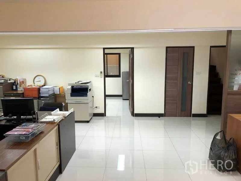 Home Office for rent in Khlong Toei, Bangkok - Bright ground-floor office area with desks, printer, glossy tiled floor and wood doors.