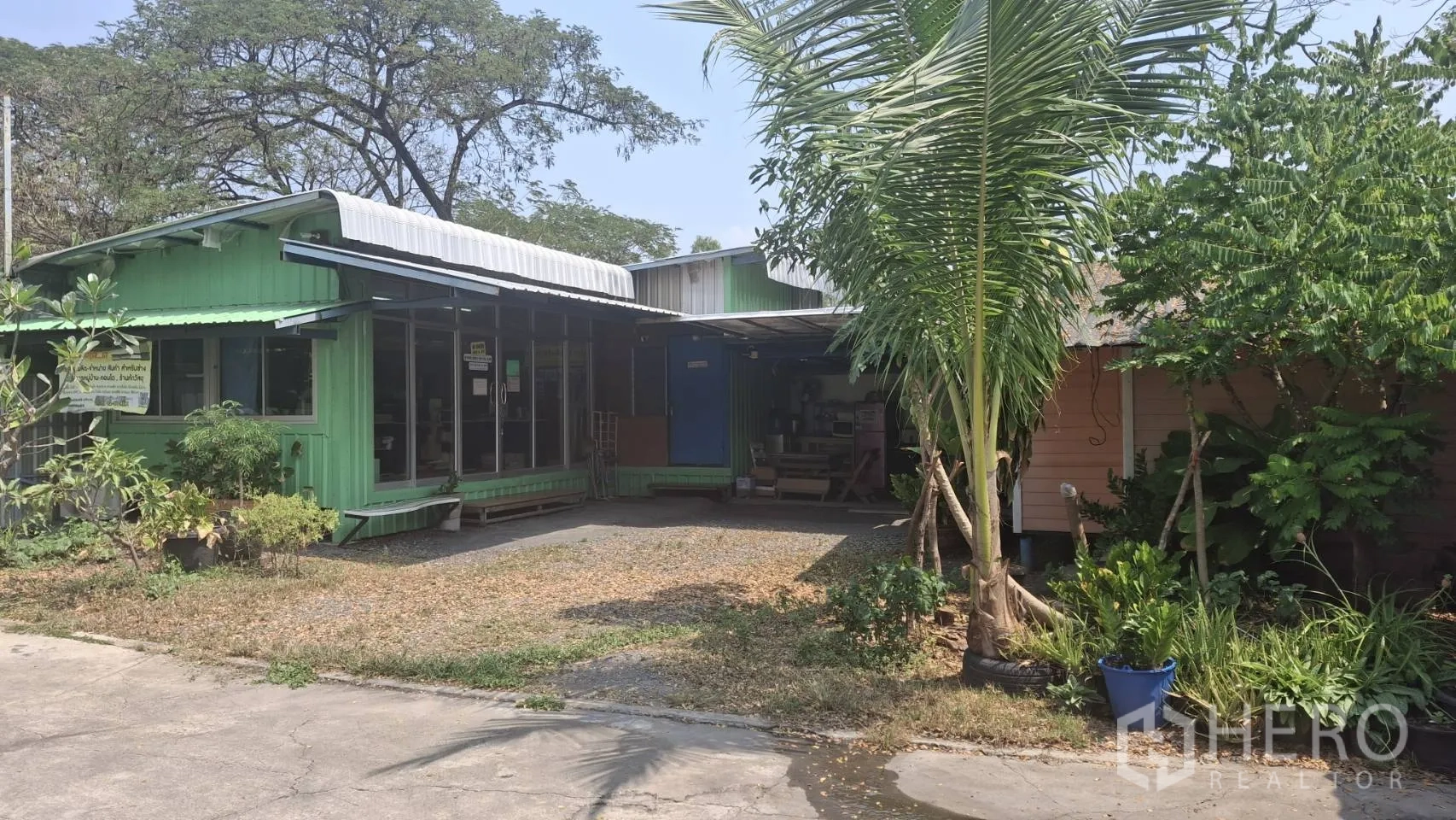 Warehouse for sale in Lam Luk Ka, Pathum Thani - Small onsite office pavilion with glass frontage and covered porch beside trees and garden within the warehouse compound.