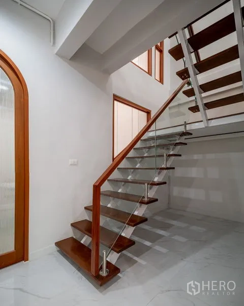 Townhouse for sale in Din Daeng, Bangkok - Modern staircase with wooden treads and glass balustrade.