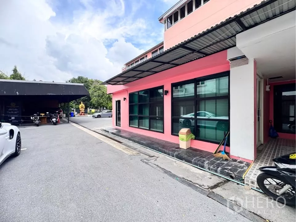 零售空间 出租在Watthana, Bangkok - 粉色低层商用建筑转角外立面，大窗与临停车通道。