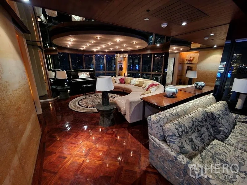 Condominium for rent in Bang Rak, Bangkok - Night view of the grand living lounge with curved sofa, piano, and warm accent lighting.