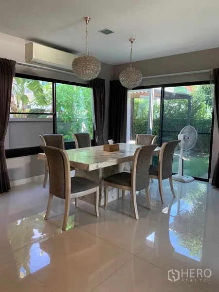 Detached House for rent or sale in Bang Phli, Samut Prakan - Dining room with marble table for six, pendant chandeliers and sliding doors opening to the garden.