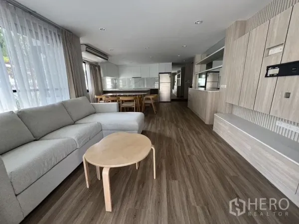 บ้าน ให้เช่าในBang Rak, Bangkok - ลิฟวิงรูมกว้าง หน้าต่างสูงพื้นจรดฝ้า พื้นไม้ และผนังทีวีบิลท์อิน