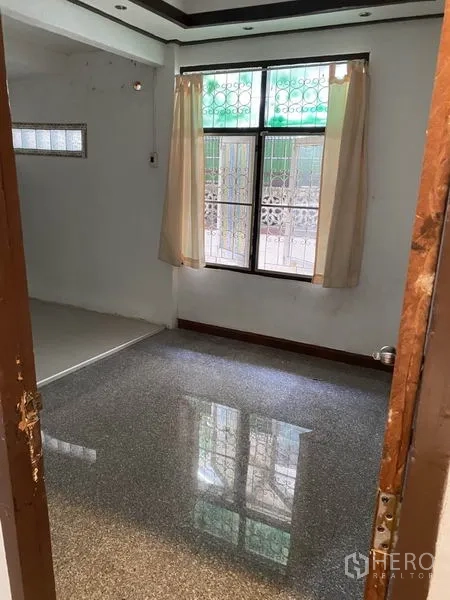 联排别墅 出租在Lat Phrao, Bangkok - 客厅铺石质地面，窗户带防盗栏与窗帘