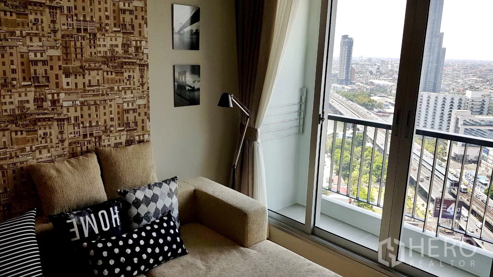 公寓 出租在Sathon, Bangkok - 客厅配沙发和落地灯，推门连通阳台，可欣赏曼谷城市全景。