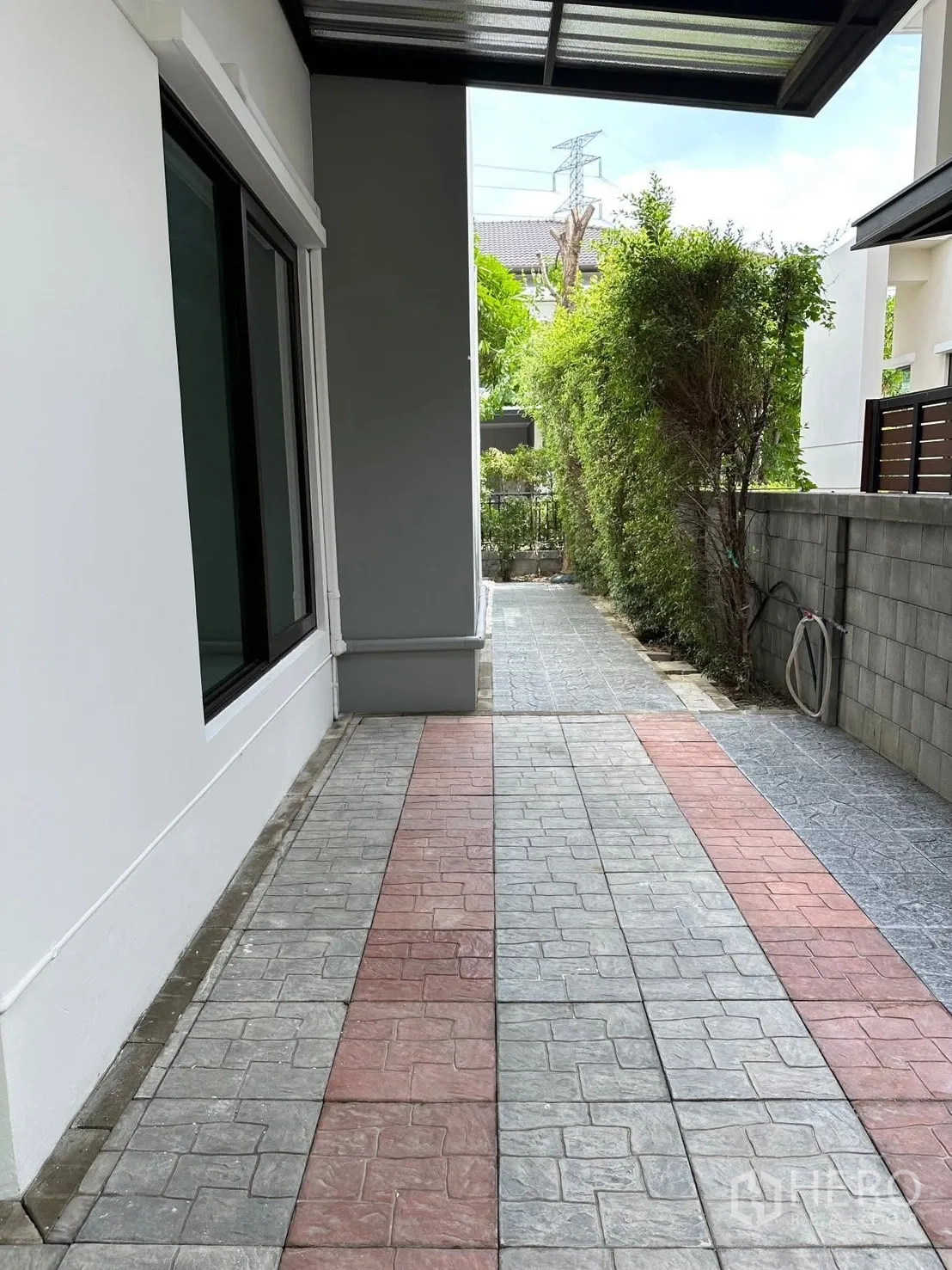 独栋房屋 for rent in Bang Phli, Samut Prakan - 带顶侧边通道，地面铺石纹砖，旁有绿篱。