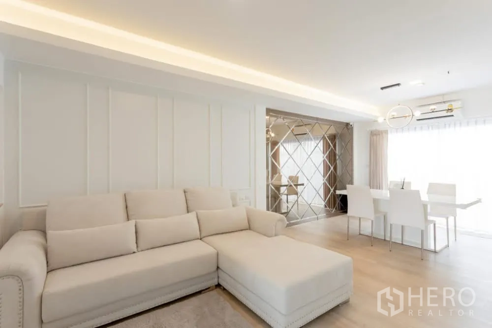 联排别墅 出租在Prawet, Bangkok - 开放式客餐厅，L型沙发、浅木地板与通高落地窗。