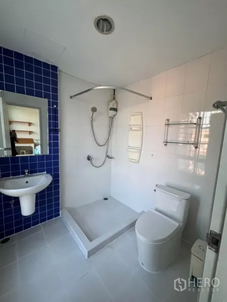 Townhouse for rent in Bang Kho Laem, Bangkok - Bright white bathroom with blue accent tiles, step-in shower and water heater.