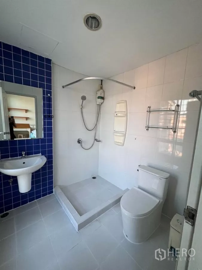 Townhouse for rent in Bang Kho Laem, Bangkok - Bright white bathroom with blue accent tiles, step-in shower and water heater.