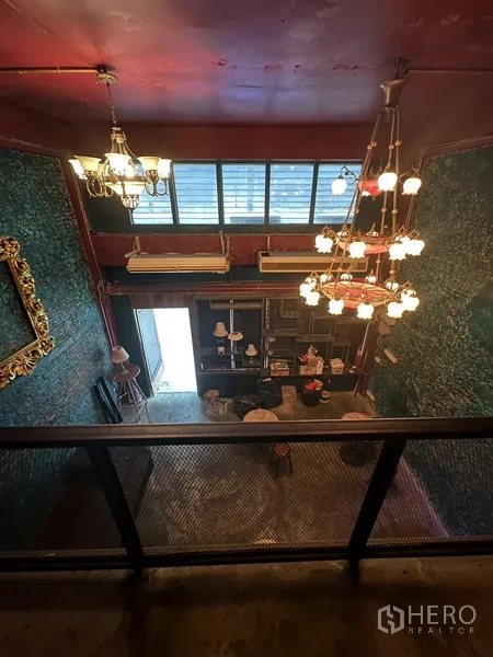 พื้นที่ขายปลีก ให้เช่า - มุมมองจากชั้นลอยลงสู่พื้นที่นั่งเล่น มีโคมระย้าหลายชุดและแอร์ติดผนัง