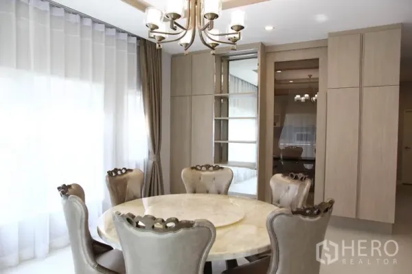 独立式住宅 出租在Bang Na, Bangkok - 优雅餐厅，圆形大理石餐桌、枝形吊灯与落地窗帘