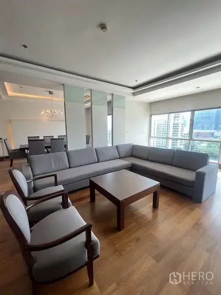 Apartment for rent in Pathum Wan, Bangkok - Living room angle showing sectional sofa, coffee table and adjacent dining area.