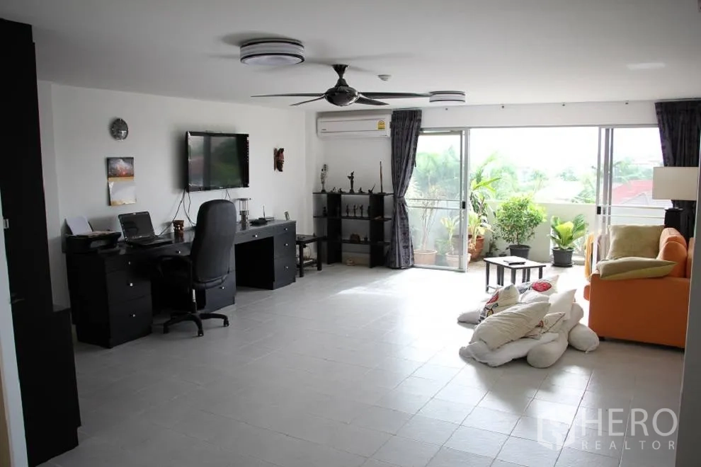 Condominium for sale in Wang Thonglang, Bangkok - Open-plan lounge with sliding doors to a balcony filled with potted plants.