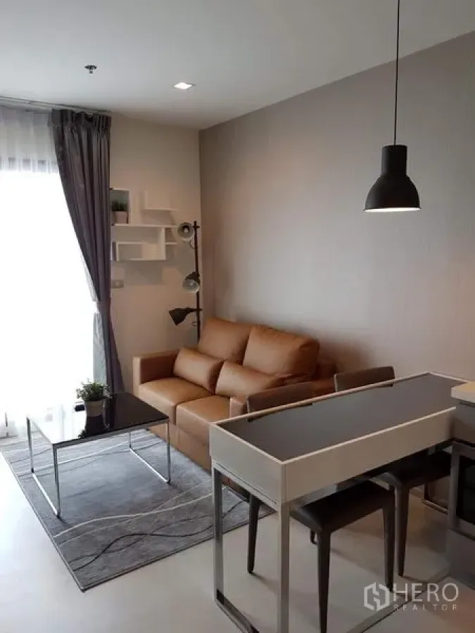 公寓 出租在Khlong Toei, Bangkok - 客厅配棕色沙发、黑色玻璃茶几与地毯，可通往阳台。