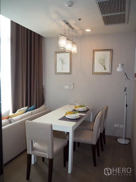 Condominium for rent in Ratchathewi, Bangkok - Cozy dining area for four with pendant lights, framed art and full-length curtains.