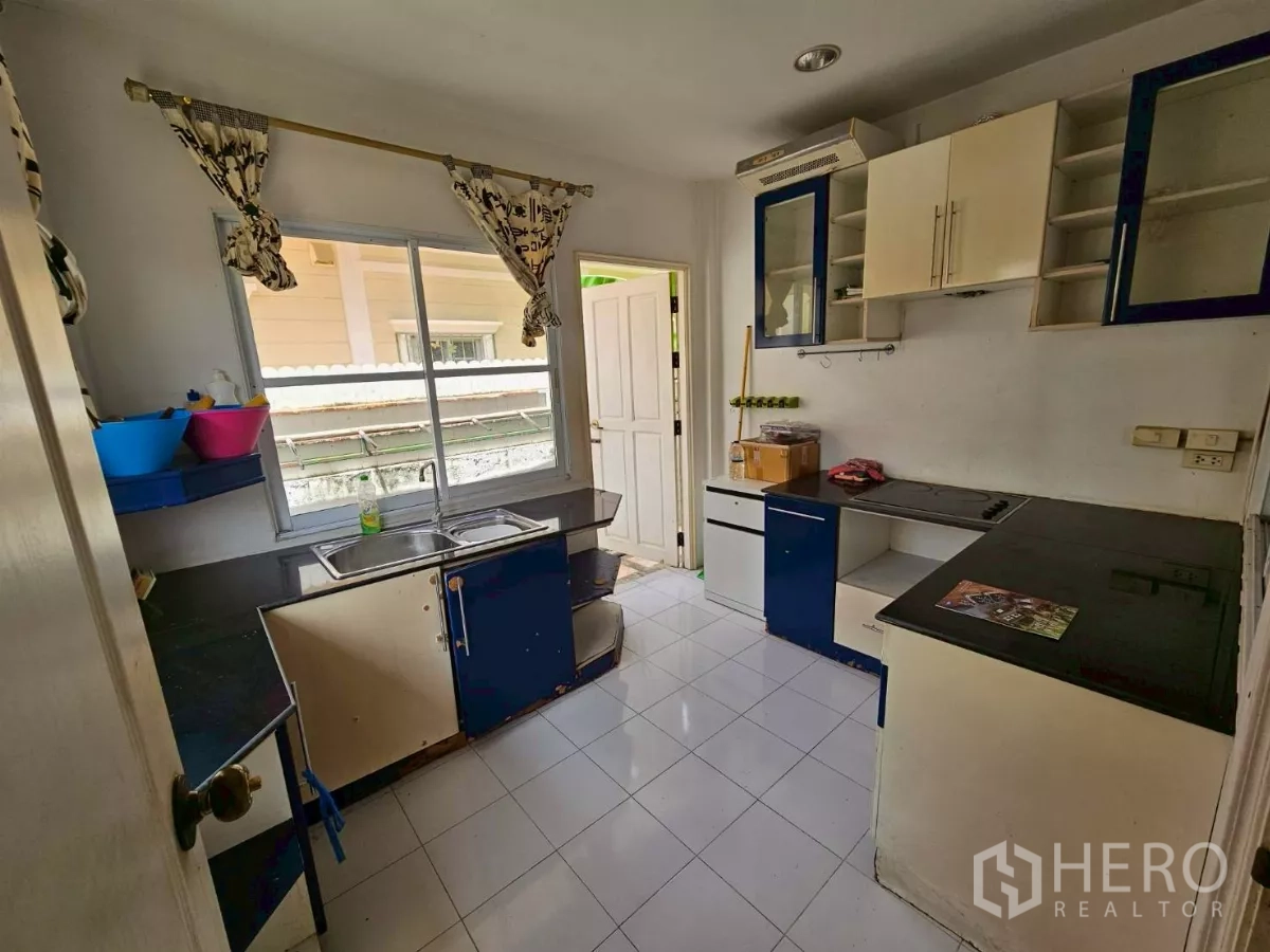 Detached House for rent or sale in Bang Lamung, Chon Buri - Compact kitchen with L-shaped counters, sink, and a large window.