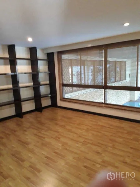 Condominium for sale - Bright room with large window, blinds, and open wall shelves.