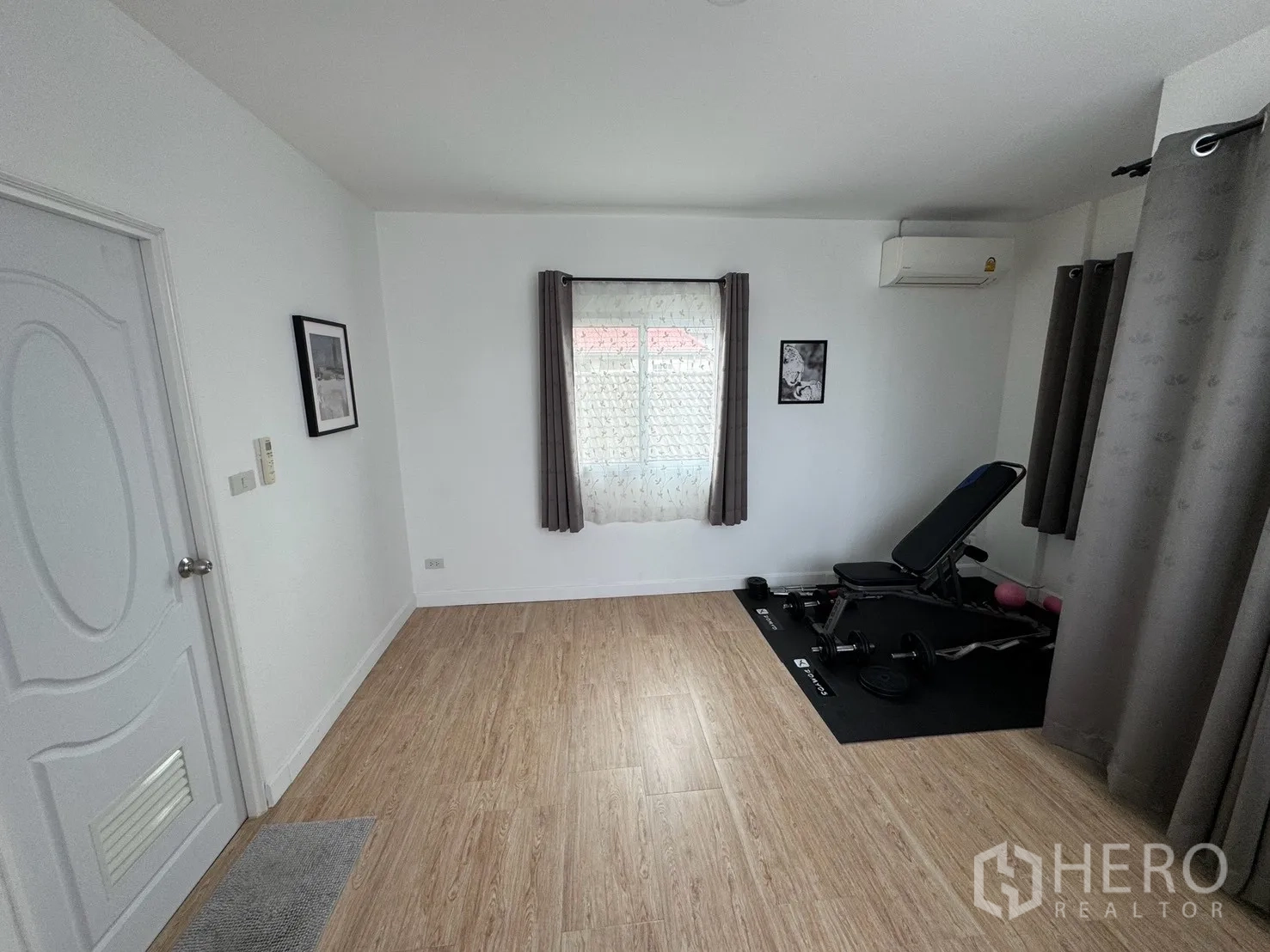 Detached House for rent in Saphan Sung, Bangkok - Multipurpose room set up as a home gym with bench, free weights, wood floors, and AC.