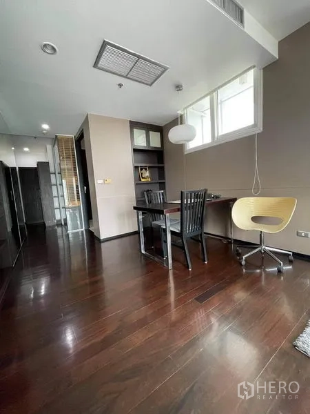 Condominium for rent or sale in Watthana, Bangkok - Workstation corner with window, desk and modern chair on dark wooden flooring.