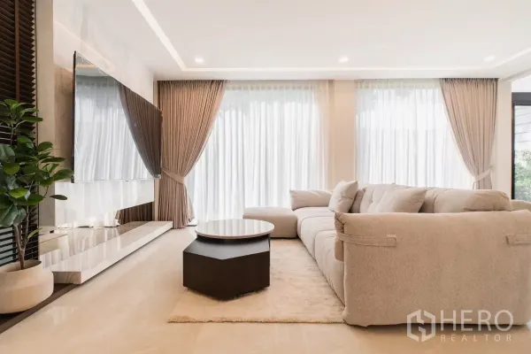 บ้าน ให้เช่าหรือขายในPrawet, Bangkok - มุมนั่งเล่นติดทีวีผนังหินอ่อน ผ้าม่านโปร่ง และไฟซ่อนเพดาน