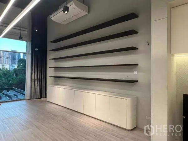 Retail Space for rent - Feature wall of long black display shelves with base cabinets beside a large window overlooking city greenery.