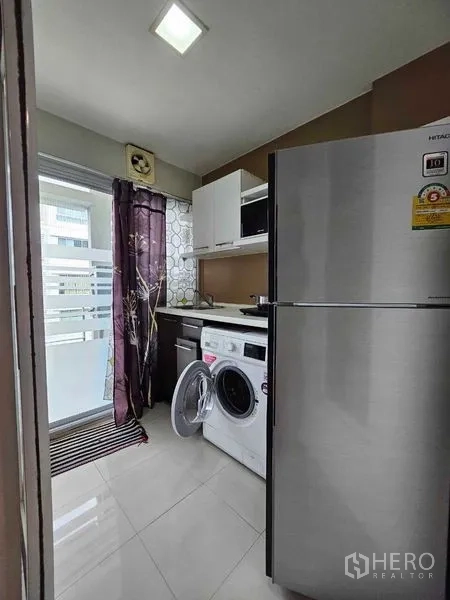 Condominium for sale in Watthana, Bangkok - Separated kitchen with stainless refrigerator, washing machine, cabinetry, and balcony access.