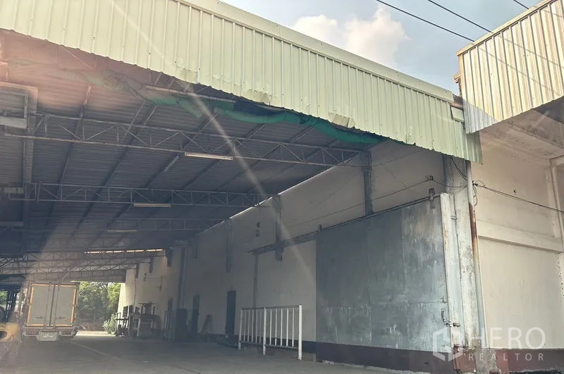 Warehouse for rent in Lat Krabang, Bangkok - Covered loading bay with high metal roof and wide truck access at a Lat Krabang warehouse.
