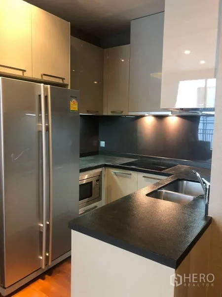 公寓 出租或出售在Watthana, Bangkok - U形现代厨房，石材台面、嵌入式烤箱与对开门冰箱。