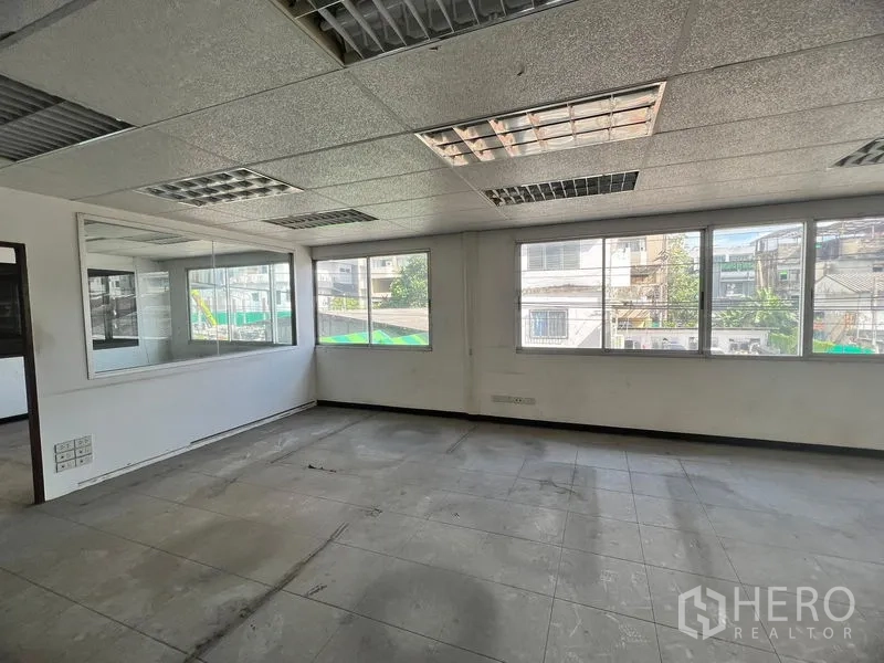 Warehouse for rent in Suan Luang, Bangkok - Office room with drop ceiling, fluorescent lights and street-facing windows.