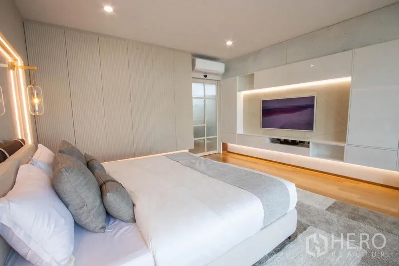 Detached House for sale in Saphan Sung, Bangkok - Master bedroom with king bed, wood flooring and a backlit media cabinet.