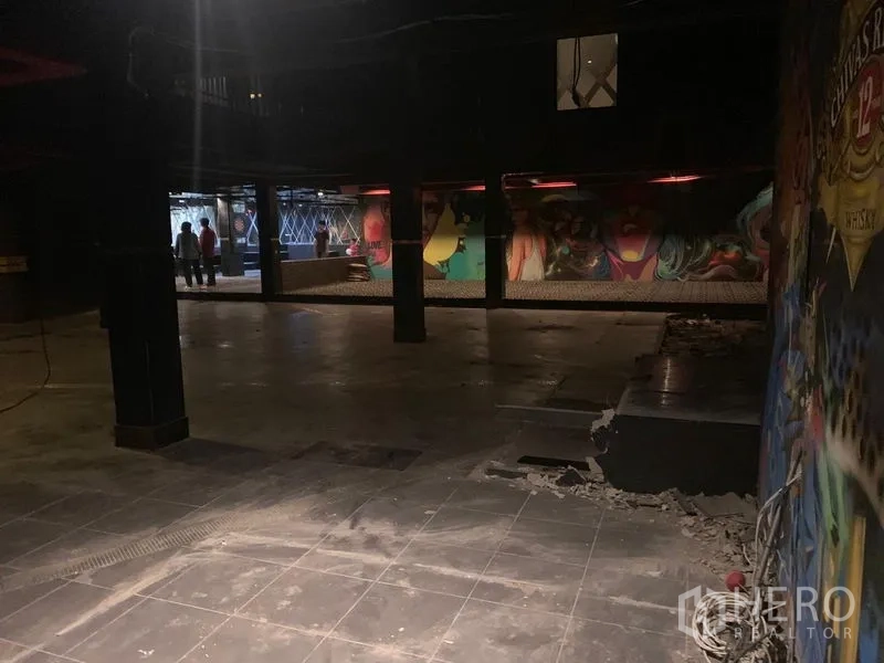 店屋 出租在Watthana, Bangkok - 开阔的工业风大厅，瓷砖地面、结构立柱和彩色涂鸦墙。