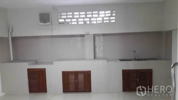 Office Space for rent in Bueng Kum, Bangkok - Long pantry with countertop, sink, ventilation blocks and wooden cabinet doors.